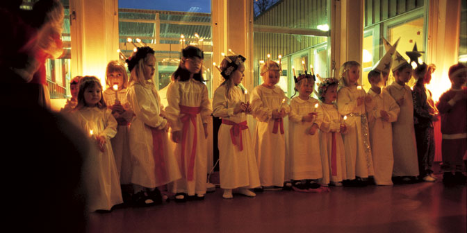 young  children dressed in sankta lucia costumes sing