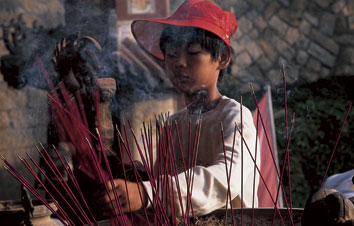 Young boy with incense offers prayers